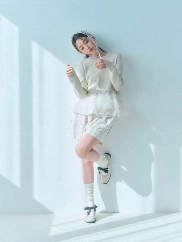 A woman in a white lace top and light shorts, with a lace bonnet