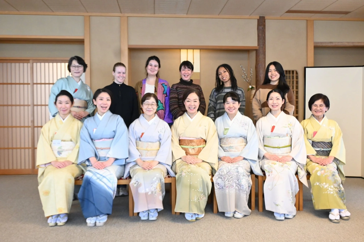 A group of women, some in kimonos and others in casual wear, smiling together in a traditional Japanese room.