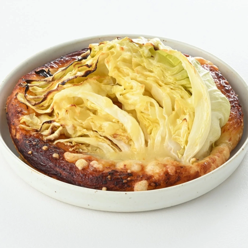 A baked dish featuring a whole cabbage, served on a white plate.