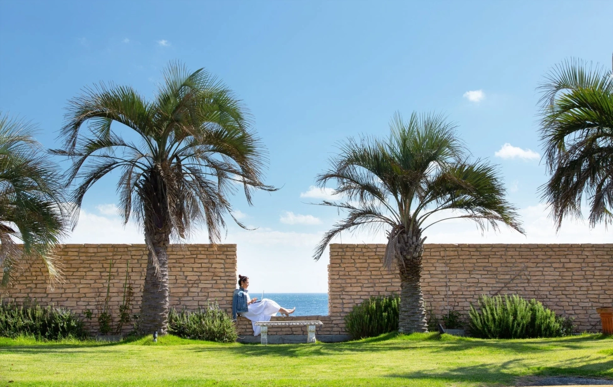 Woman working on laptop by the sea at a resort