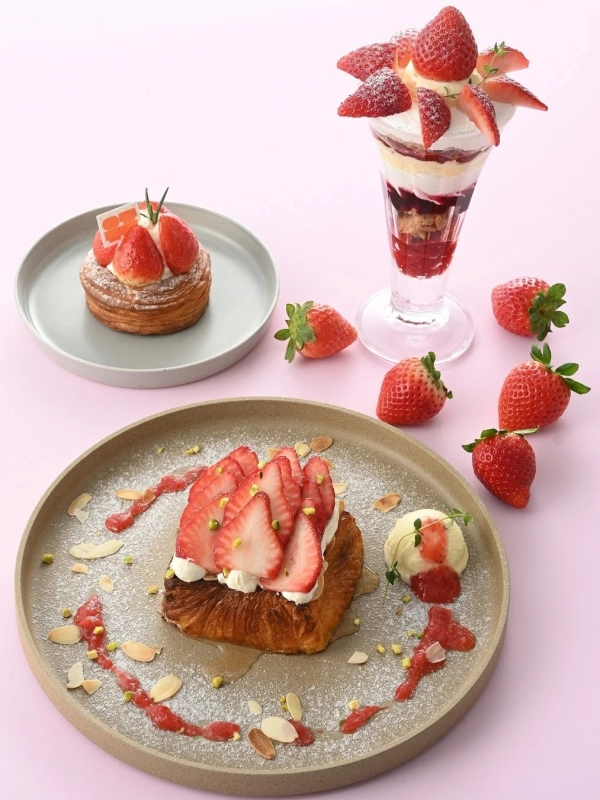 A vibrant array of strawberry desserts, including a parfait, French toast, and Danish, set against a pink background.