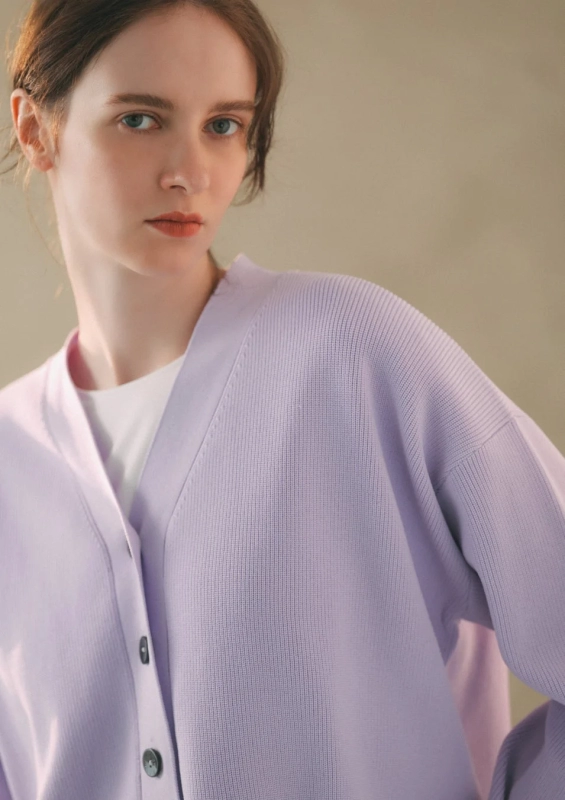 A woman wearing a pale lavender V-neck cardigan, exuding calm and elegance.