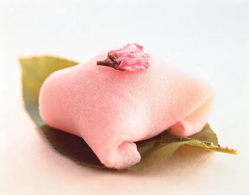 A delicate pink wagashi on a green leaf