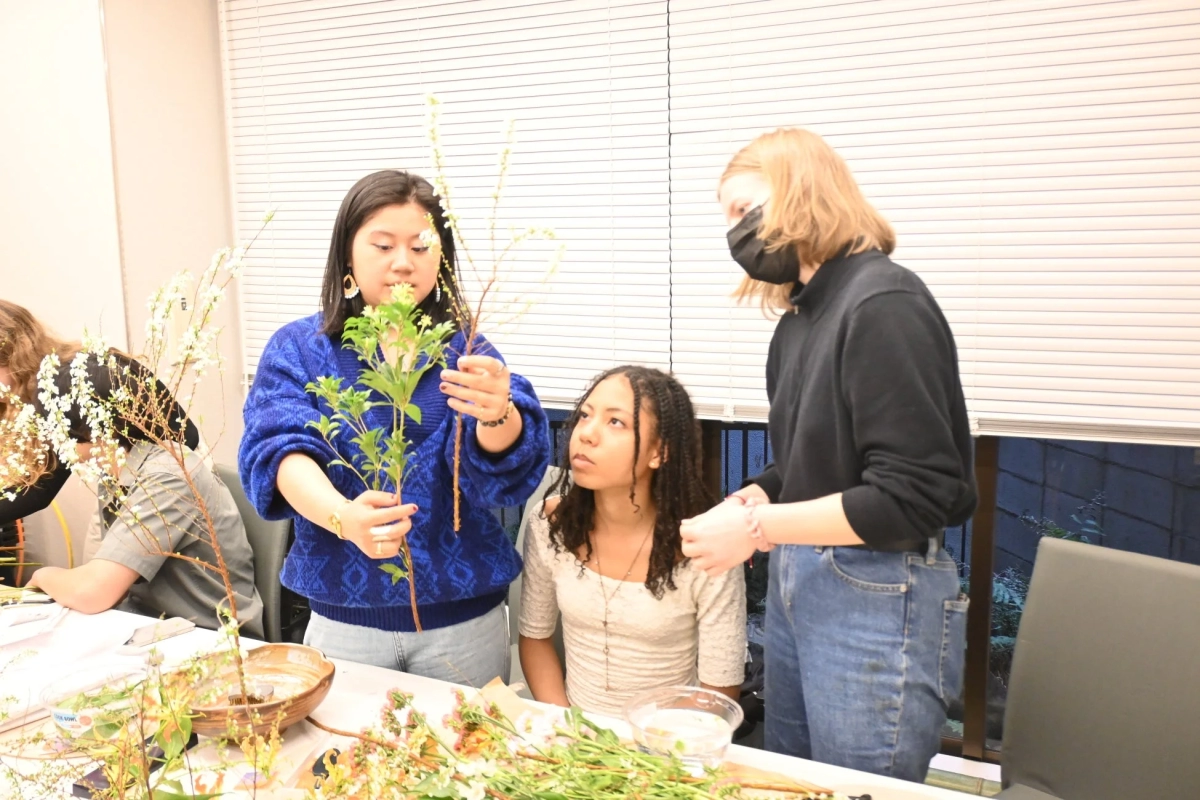 Multiple women engaged in an Ikebana workshop, focusing on arranging flowers and plants.