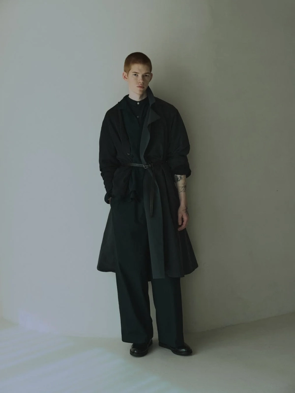 A male model in a dark, minimalist mizuiro ind outfit