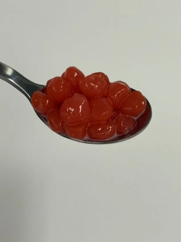 A close-up of vibrant red tapioca pearls on a silver spoon