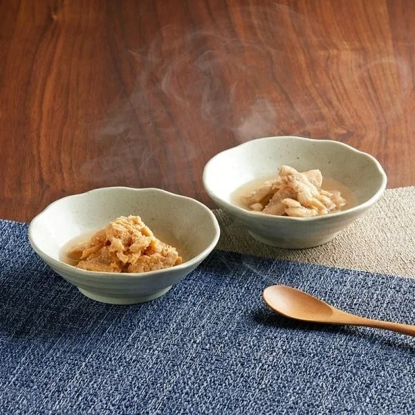 Two bowls of steaming, warm pet food with wooden spoons, suggesting healthy and delicious meals.