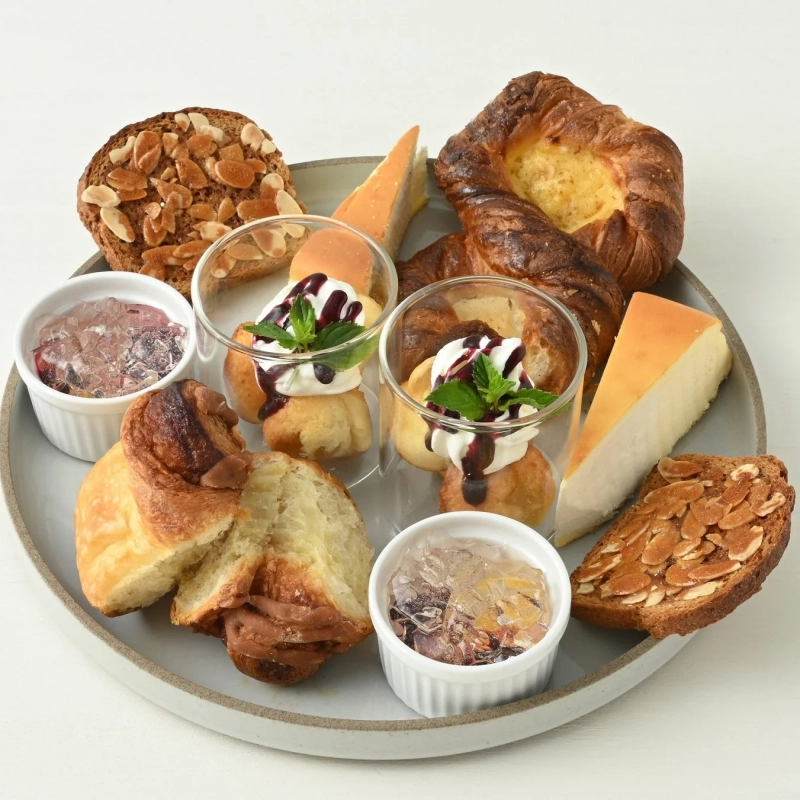 A lavish plate featuring various breads, pastries, and desserts like cheesecake, topped with cream and berries.