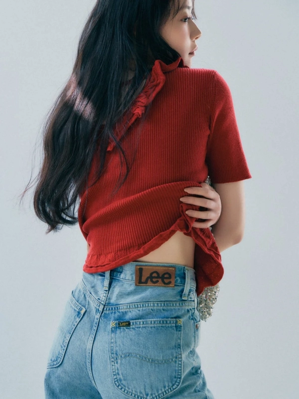Model in red ribbed top and light blue jeans