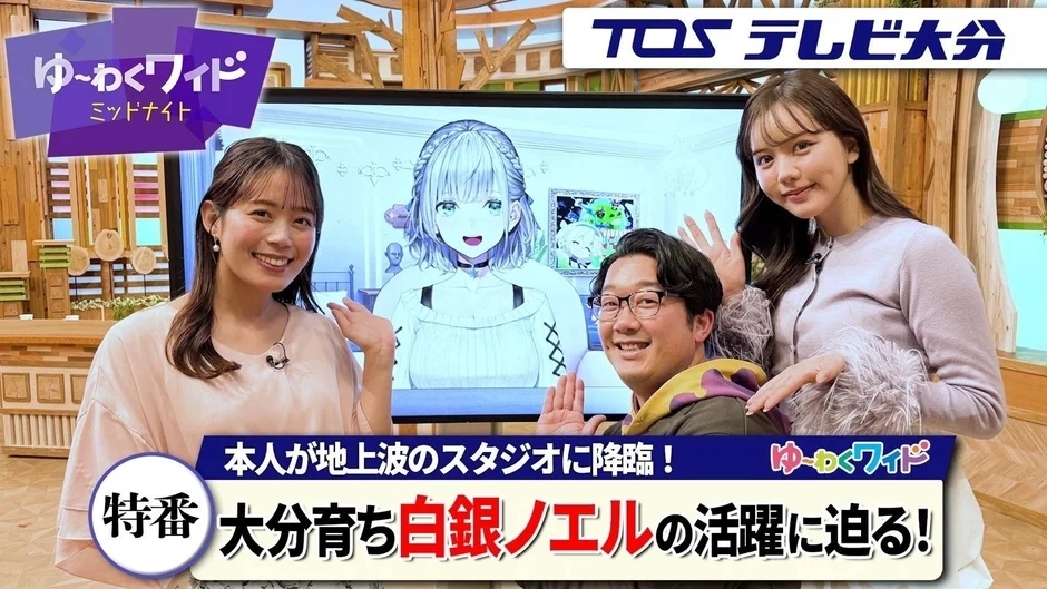 TOSテレビ大分の「ゆ~わくワイド ミッドナイト」特番で、大分出身のVTuber白銀ノエルが地上波スタジオに降臨した様子を伝える。2人の女性と1人の男性タレントが笑顔で出演している。