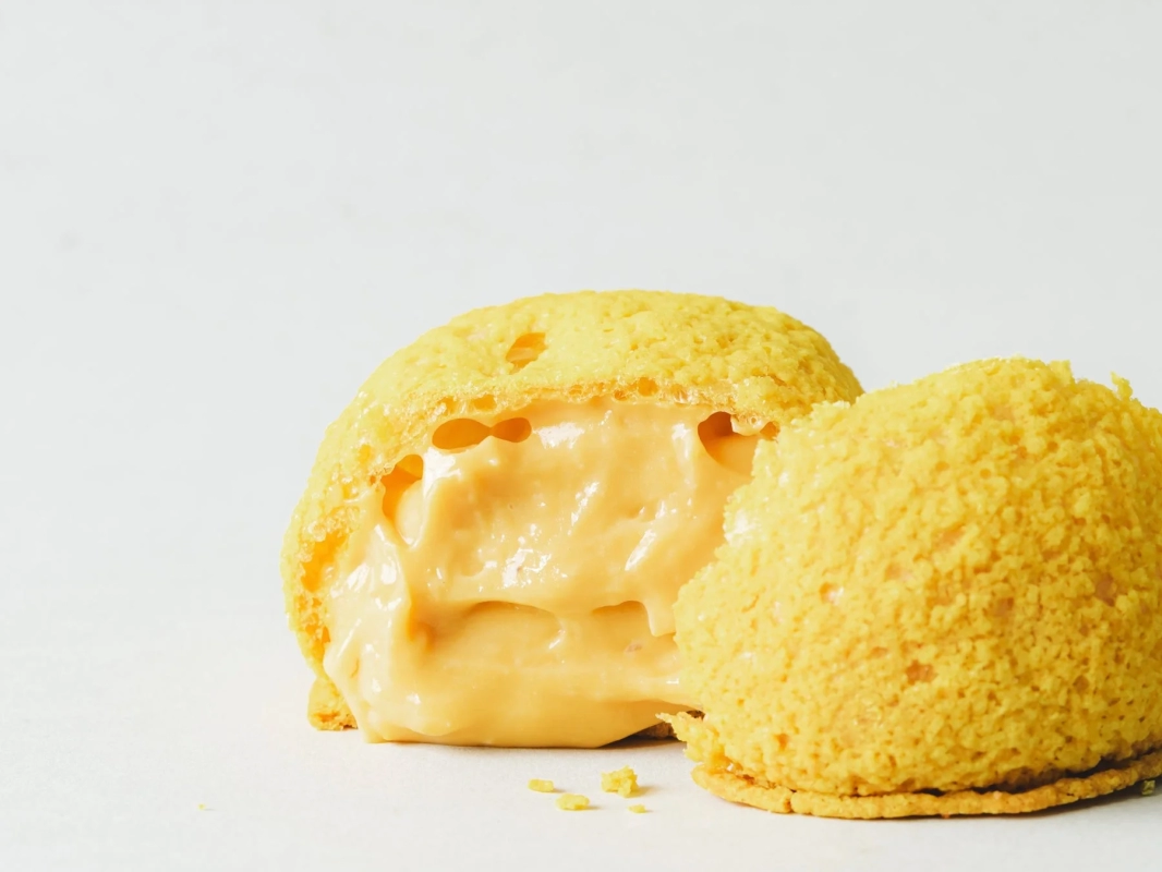 A classic cream puff, sliced in half to showcase its rich, flowing custard cream.
