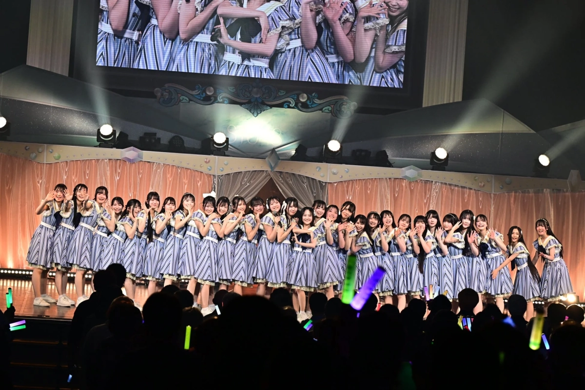 A group of female idols performing on stage with striped costumes