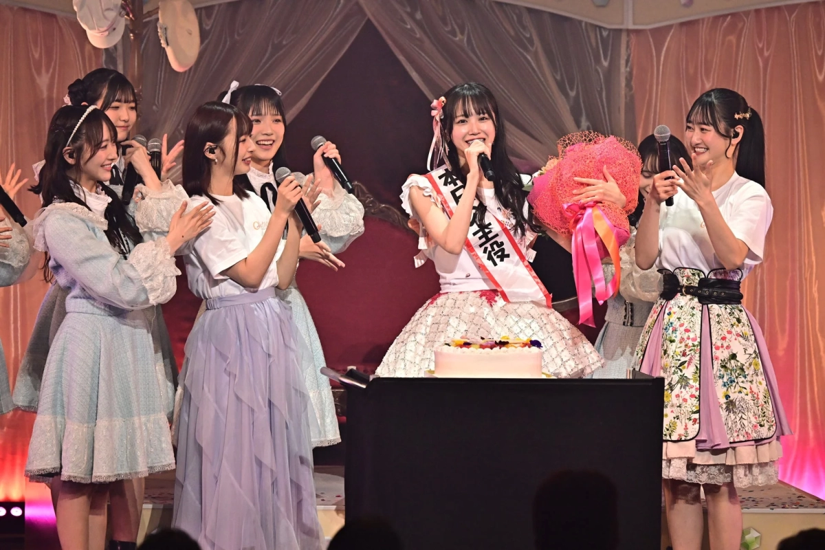 Idol group members celebrating on stage with a cake and flowers
