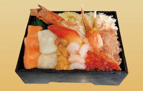 A lavish seafood bento box filled with various fresh ingredients like salmon, scallops, sea urchin, shrimp, crab, and salmon roe.