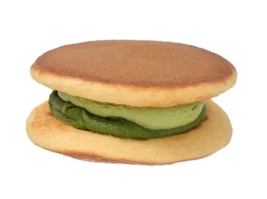 A close-up of the Niso no Uji Matcha Nama Dorayaki, revealing vibrant green matcha filling between fluffy dorayaki pancakes.