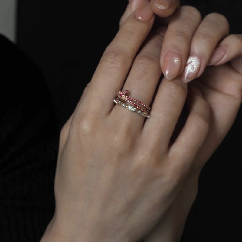 Hand wearing a pink gemstone ring and a pearl ring